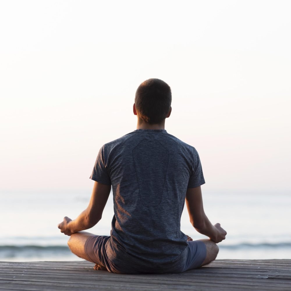 back-view-man-meditating-beach